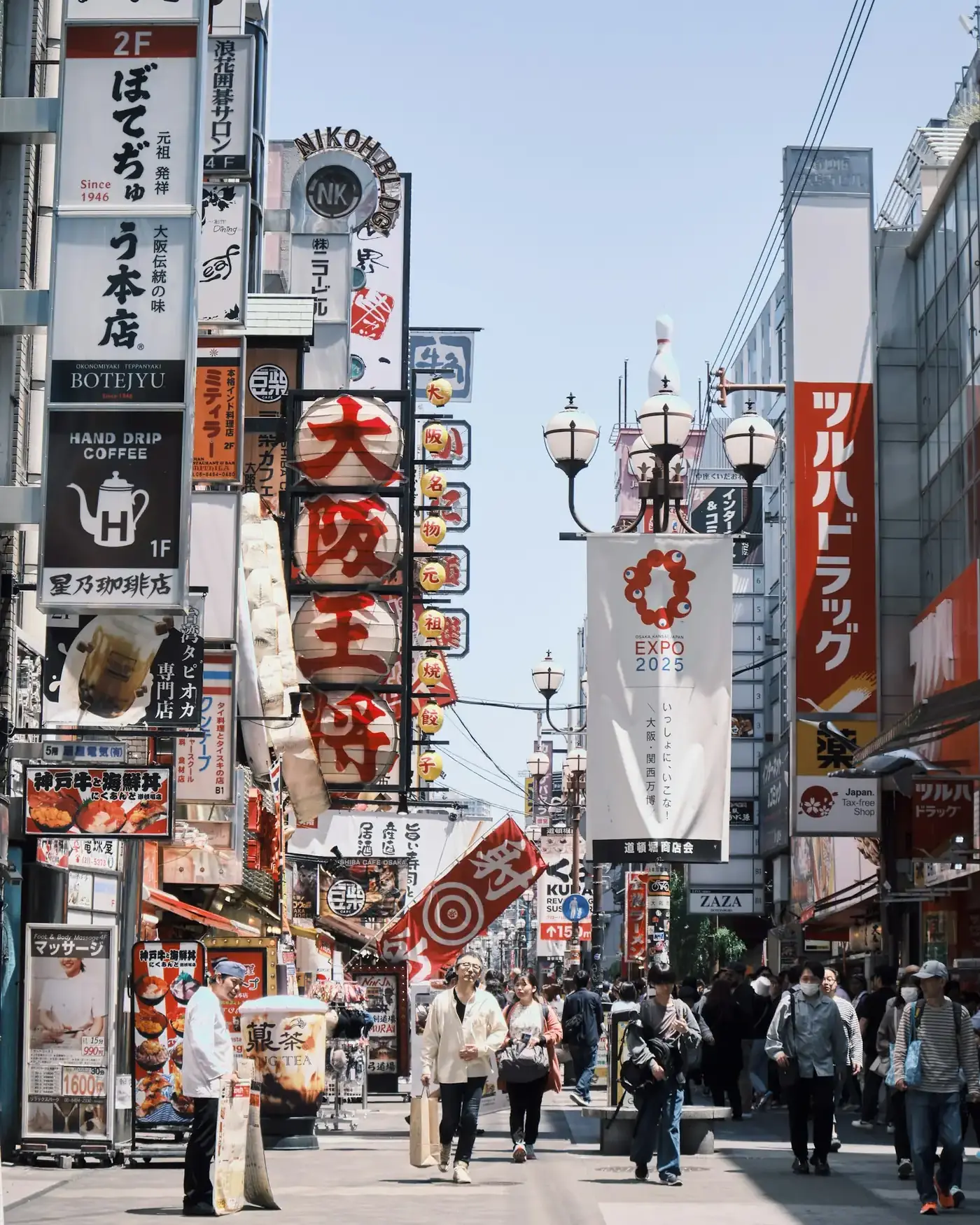 A busy shopping street in Shinsekai, Osaka, with Tsutenkaku tower