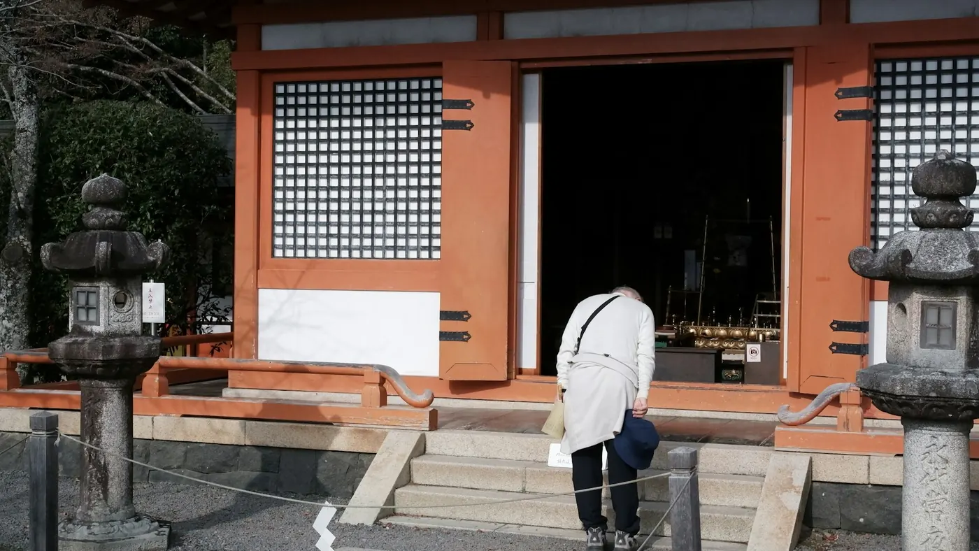 A person bowing at the entrance of a Japanese temple