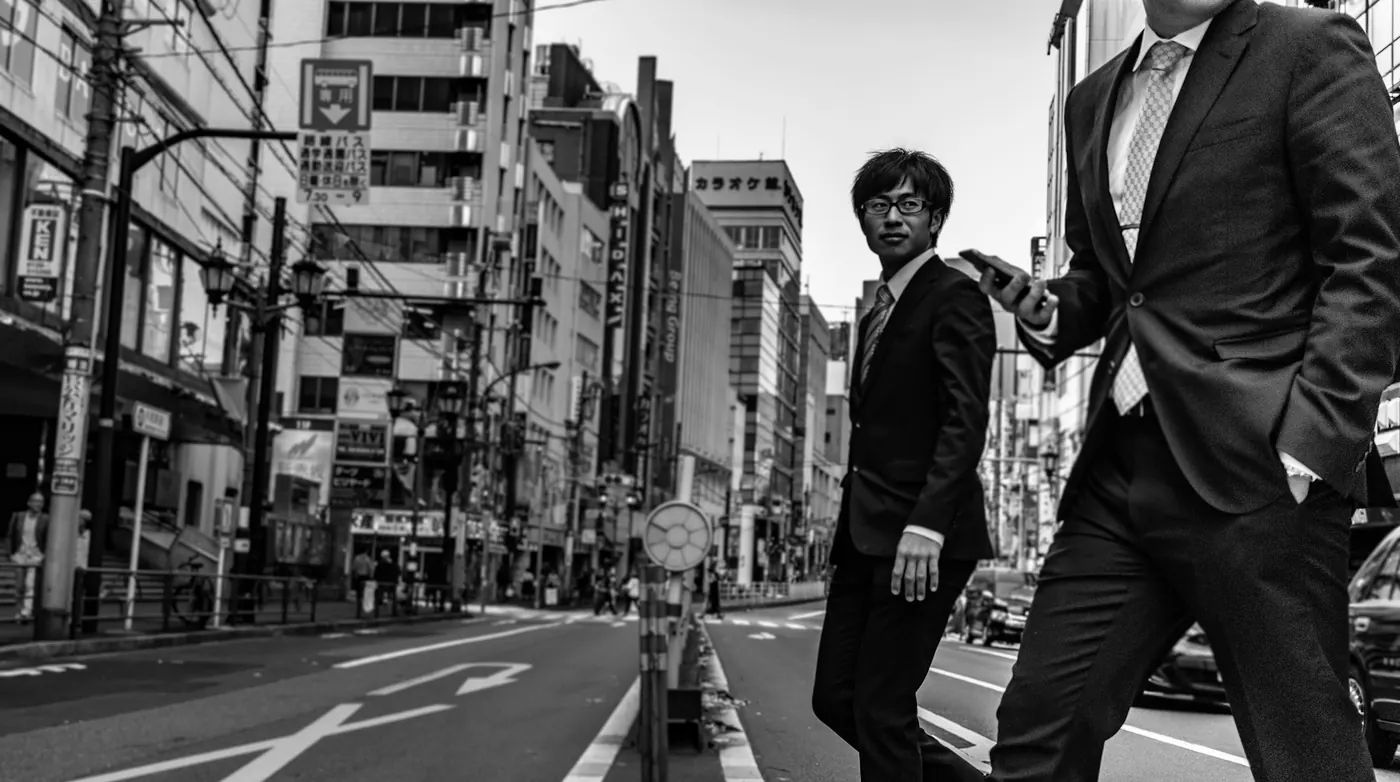 Two businessmen in suits walking and talking on a Tokyo street