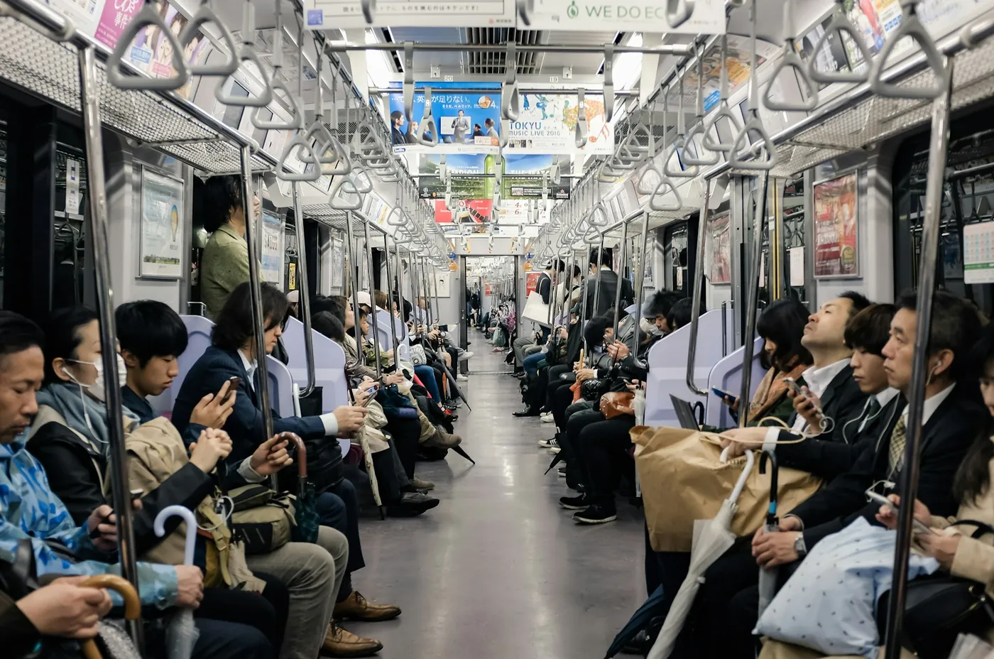 A row of Japanese commuters sitting on a long bench seat