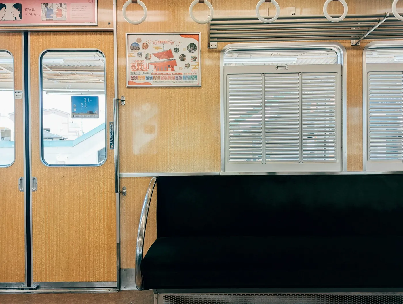 An empty green bench seat beside the door of a Japanese train