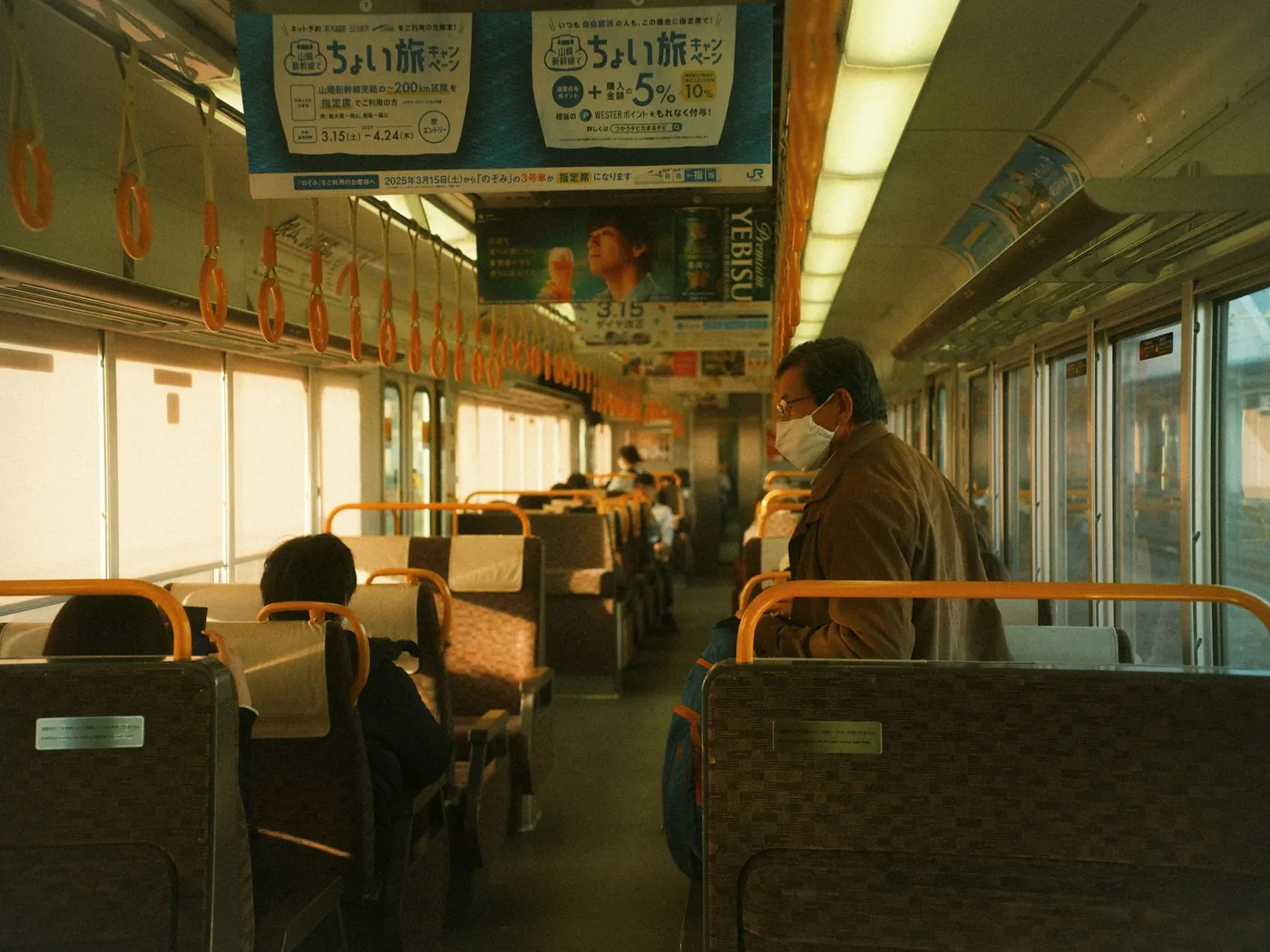 An evening train car with warm light and a few passengers
