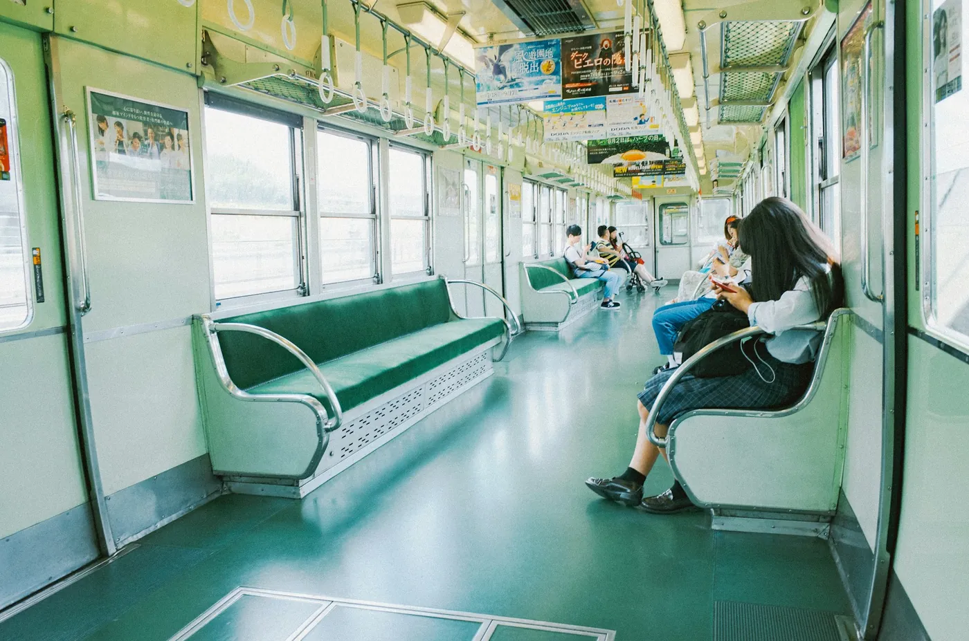 A calm, half-empty train car with green seats