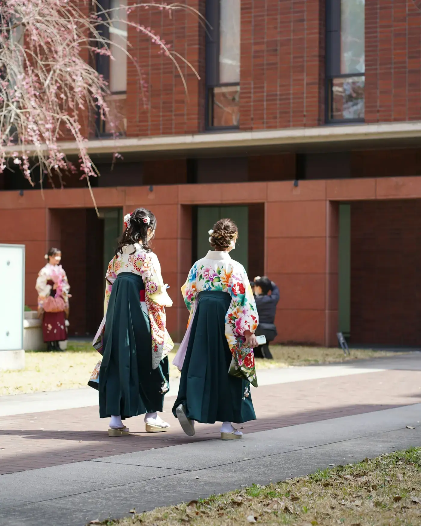 A young woman in hakama walking across a university campus