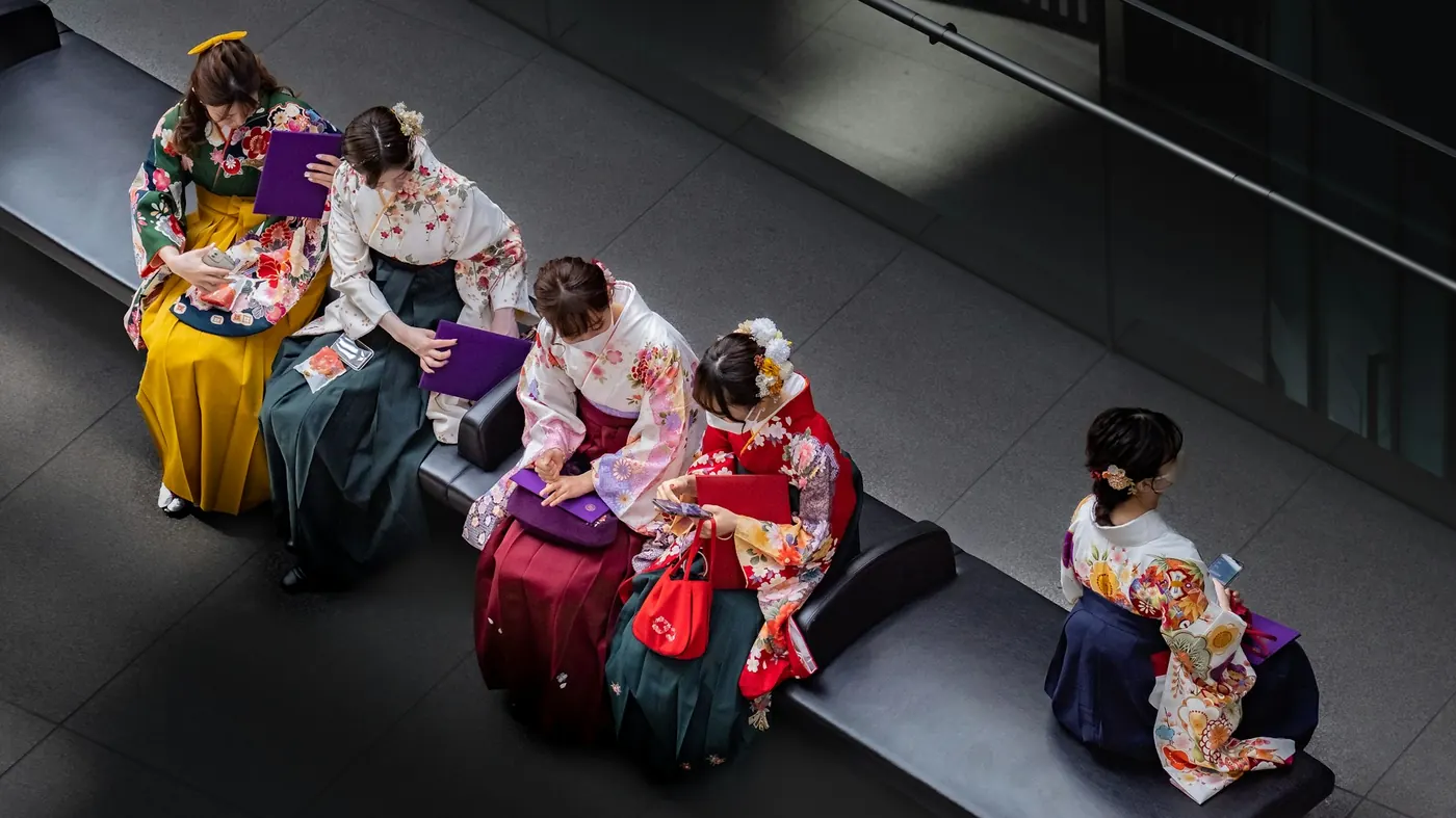 Japanese graduates in colourful hakama sitting on a bench on graduation day