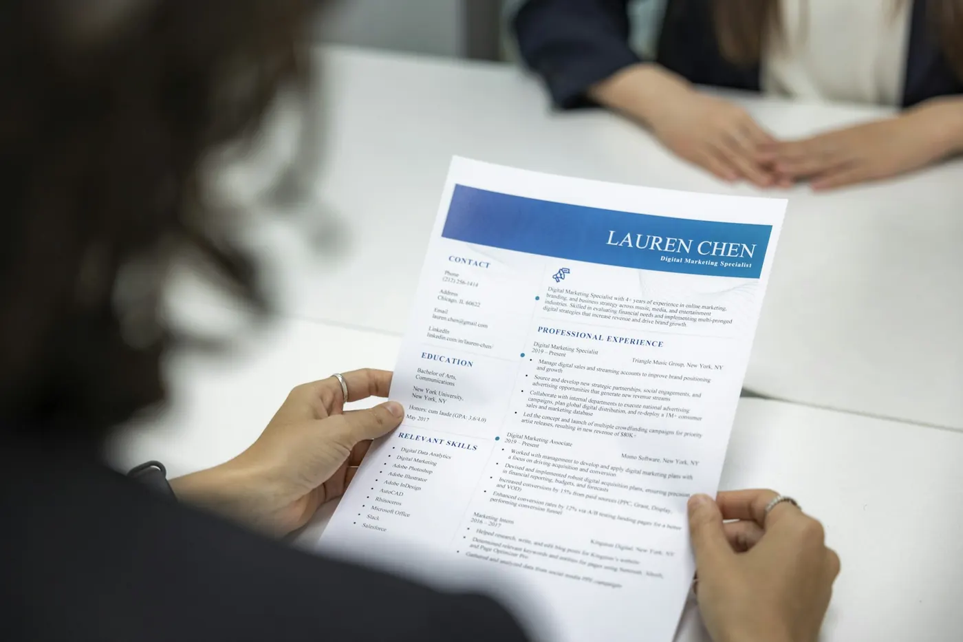 A person reading a printed CV at a table